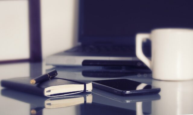 computer, laptop, in a working environment, coffee, coffee cup, pen, notebook, desk, work, home offices, cellphone, organization, computer, computer, coffee cup, pen, desk, desk, work, work, work, work, work, cellphone, cellphone