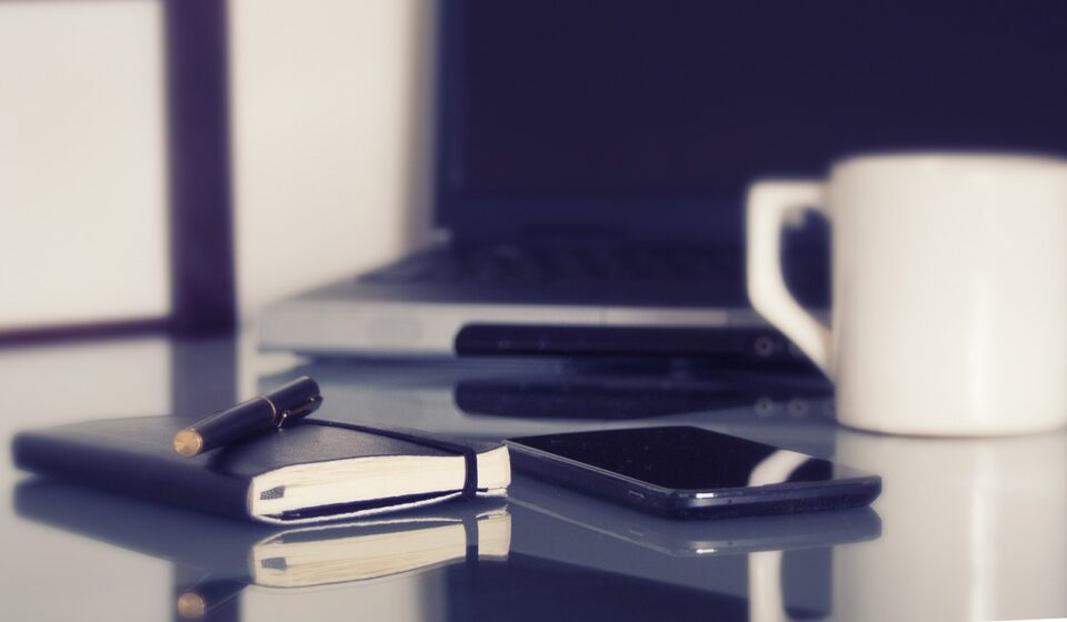 computer, laptop, in a working environment, coffee, coffee cup, pen, notebook, desk, work, home offices, cellphone, organization, computer, computer, coffee cup, pen, desk, desk, work, work, work, work, work, cellphone, cellphone